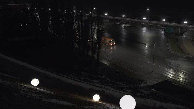city bus arriving to terminal by dark rainy night 
