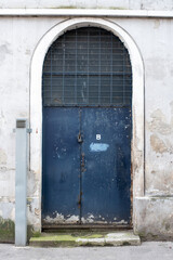 Old metal blue door with cracked paint and wall, with old lock and grid