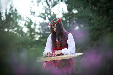 Beautiful young woman playing harp in woodland,fantastic evening sunlight