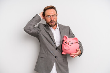 middle age man feeling stressed, anxious or scared, with hands on head. businessman and a pigy bank...