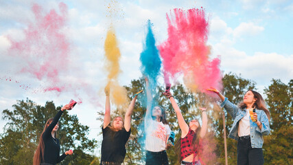 Cheerful girls toss up multi-colored powder. Holi holiday.
