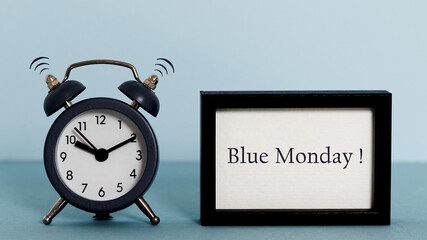 Blue Monday ringing alarm clock and text in frame. Blue Monday warning concept.