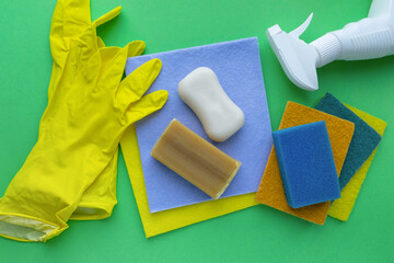 Flat lay of various cleaning products and items on green background, top view