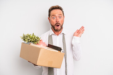 middle age man looking surprised and shocked, with jaw dropped holding an object. unemployment...