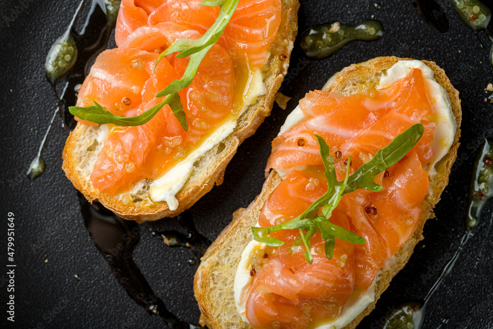 Wall mural Bruschetta with salmon and cheese on black plate macro close up top view - Wall murals