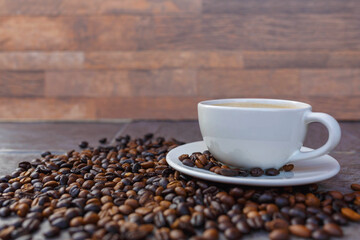 A cup of coffee and roasted coffee beans in a brown bag.
