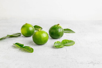 fresh green lime and lime leaves on white wooden table