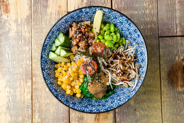 eel poke, edamame, cucumbers, corn, chukka, tomatoes and boiled rice top view on wooden table