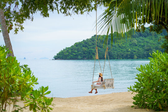 girl relaxing on a swing on the beach in summer alone on vacation