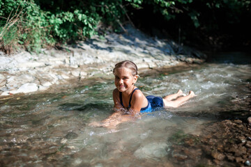 Happy preteen girl bathing in stream canyon river in the mountains, nature pool. Cold water, hardening and natural spa procedure, wildlife and green tourism, summer holidays