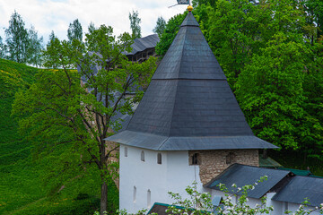 View of beautiful buildings and orthodox churches ancient Pskov-Pechersky monastery. Fortress wall and tower. Pechory, Pskov, Russia.