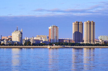 Fototapeta na wymiar Russian-Chinese border along the Amur River. View from the embankment of the city of Blagoveshchensk, Russia to the city of Heihe, China. A mixture of architectural styles. The time of the golden hour