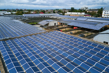 Aerial view of solar power plant with blue photovoltaic panels mounted on industrial building roof...