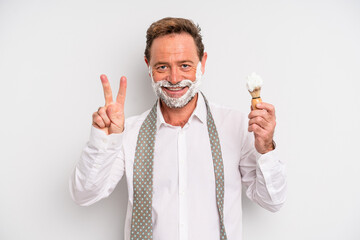 middle age man smiling and looking friendly, showing number two. shaving brush and foam concept