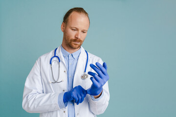 White male doctor with stethoscope wearing medical gloves