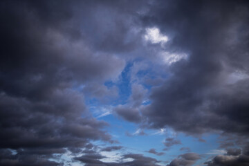 Obraz premium Epic Dramatic storm dark grey cumulus rain clouds against blue sky background texture, thunderstorm