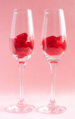 Romantic card with wineglasses on a pink background filled with silk hearts. Cute gift for lovers for valentine's day, anniversary, wedding. Vertical photo