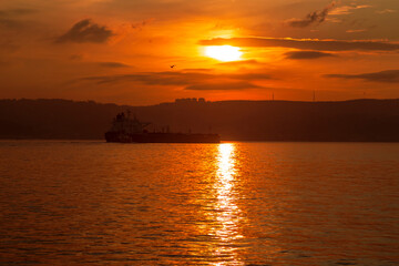 Fototapeta na wymiar big ship with sunset. orange sky and clouds