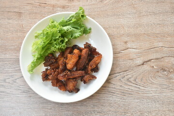 crispy fried pork belly with chili sauce and lettuce on plate