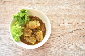 spicy fried pork bone with coconut milk curry on lettuce in bowl