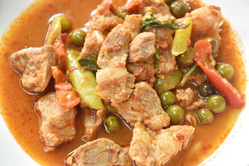 spicy fried pork bone with eggplant in coconut milk curry on lettuce in plate
