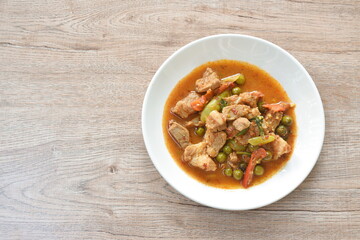 spicy fried pork bone with eggplant in coconut milk curry on lettuce in plate