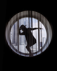 Silhouette of woman wearing hat standing in the round window