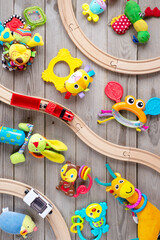 Top view of kids toys on floor on wooden background. Educational toys blocks, train, railroad, plane. Toys for nursery, preschool and kindergarten or daycare. Kids toys frame on wood background.