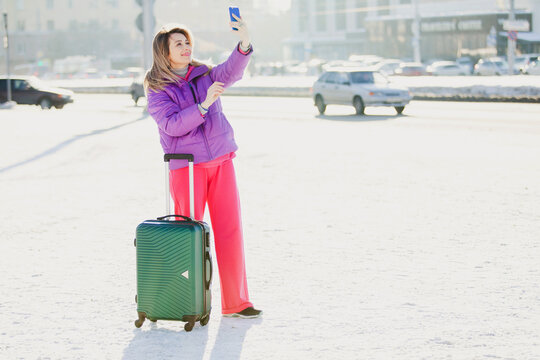 an adult woman on the street in winter with a suitcase