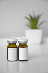 Cosmetic bottle for injection on the background of a syringe and a green flower.