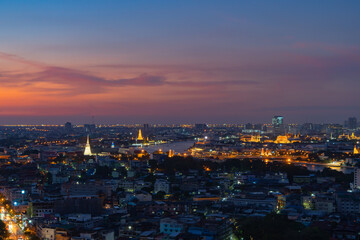 Fototapeta na wymiar Aerial view of White Prayoon Pagoda, Memorial Bridge, and Phra Pok Klao Bridge with buildings and curve of Chao Phraya River at sunset. Urban city, Downtown Bangkok, Thailand.