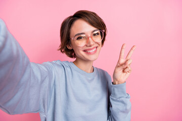 Fototapeta Self-portrait of attractive cheerful girl showing v-sign good mood isolated over pink pastel color background obraz
