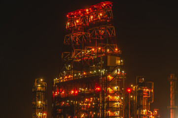 An oil and gas processing plant. Technological installation at an oil refinery. Lighting of factory equipment at night. The light from the lamps at the enterprise. Coke production plant.