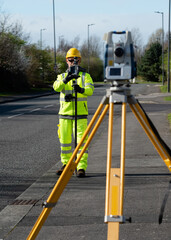 Site engineer doing road survey using modern robotic total station EDM before begining of construction works and setting construction site