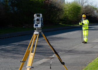 Site engineer doing road survey using modern robotic total station EDM before begining of construction works and setting construction site