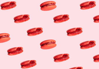 Red macarons against pastel pink background. Creative pattern, traditional popular meringue based cookies. 