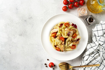 Pasta salad with grilled chicken, tomatoes and olive oil in a plate on a light culinary background. A traditional Italian dish is girandole or fusilli with fried poultry fillet and vegetables top view