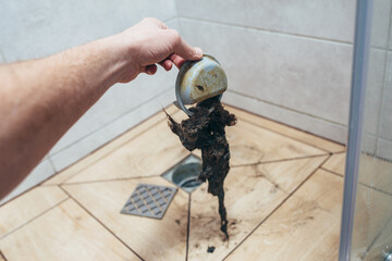 Water drain is clogged with hair. Close-up of drain.