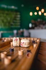 Sweet colorful French macaroon cookies dessert on brown wooden board game. Theme of rest at home during quarantine