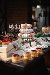 Sweet colorful French macaroon cookies with other dessert. Vertical view for social media