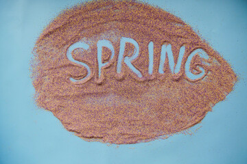 Spring hand written concept on sand in shape of leaf. Colorful sand. Creative spring text concept....