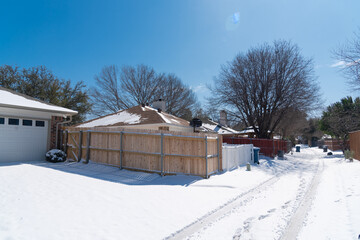 Snow covered the back alley of residential houses roofs and wooden fence after the historic blizzard near Dallas, Texas, USA