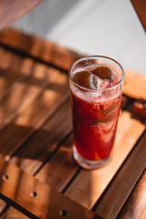 Summer red drink coctail in glass jar, with fresh berries on wooden table