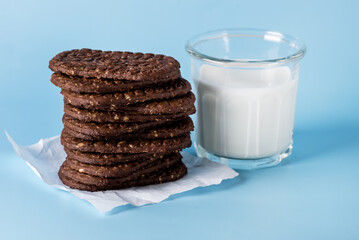 Stack of Delicious Chocolate Cookies with Oatmeal and Glass of Milk on Blue Background Copy Space Tasty Homemade Cookies