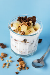 Glass of Diet Dessert with Yogurt Muesli or Granola Diet Cookies with Oatmeal and Fruit Blue Background Healthy Diet Breakfast Vertical