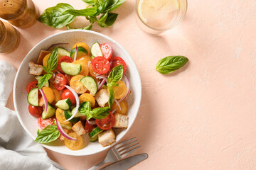 Tuscan Panzanella with tomatoes and bread on sunny pink background. Top view. Traditional Italian cuisine. Vegetarian panzanella salad. Mediterranean healthy food.