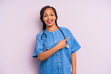 black afro woman looking excited and surprised pointing to the side. nurse concept