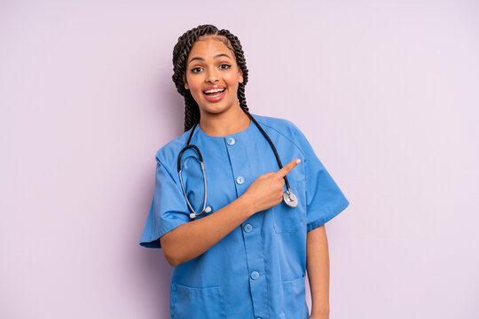 Black Afro Woman Looking Excited And Surprised Pointing To The Side. Nurse Concept