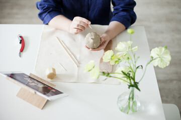 woman sculpting a pumpkin out of clay with tools - hobby and DIY project at home