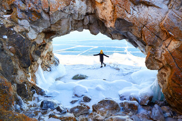 A happy girl travels on Lake Baikal in winter. Beautiful winter landscape, arch in the rock.